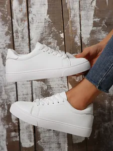 Side profile of white casual low-top platform sneakers worn with denim jeans