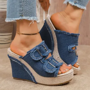 Detailed view of women's denim wedge sandals with fringe trim and buckle straps.