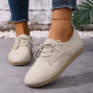 Close-up of stylish beige suede-like lace-up casual flats worn with blue denim jeans