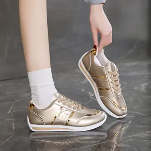 Dettaglio di sneaker dorate metallizzate da donna su sfondo di marmo grigio scuro
