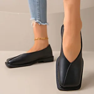 Primer plano de elegantes zapatos planos negros con punta cuadrada y diseño de cuello en V
