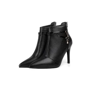 Detailed view of women's black quilted pointed-toe ankle boots with gold chain