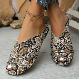 Close-up view of ethnic paisley print flat sandals with Roman-style cross straps on feet.