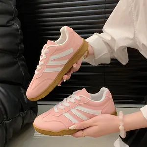 Vue détaillée de baskets rétro roses style German Trainer avec rayures blanches.
