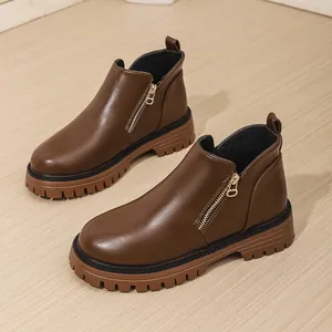 Detailed view of brown leather Martin boots with thick rubber soles and side zippers