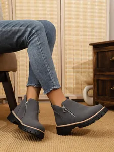 Close-up of women's grey suede ankle boots with side zippers and chunky lug soles