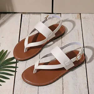 Detailed top view of white flat thong sandals with ankle straps on a wooden deck.