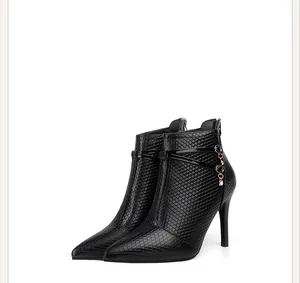 Macro view of black pointed toe stiletto ankle boots with textured leather and rhinestone charm