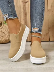 Macro view of tan suede slip-on sneakers featuring thick white platform soles and elastic