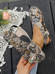 Close-up detail of ethnic paisley print fabric on bohemian flat toe-loop sandals for women