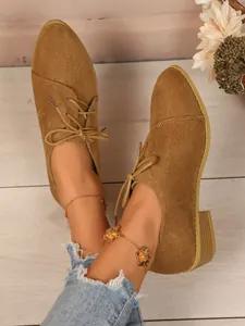Detail view of women's tan corduroy pointed toe lace-up shoes on wood floor