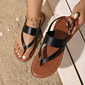 Close-up of black flat thong sandals with brown sole and adjustable ankle strap