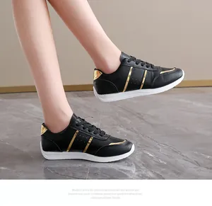 Vista laterale di sneakers casual nere con strisce dorate su pavimento in marmo