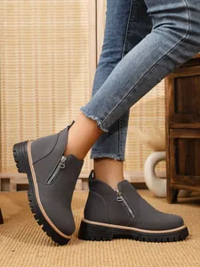 Close-up view of grey suede ankle boots with side zipper and chunky sole