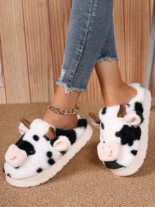 Close-up detail of cute cow-patterned plush slippers with fuzzy ears and horns for winter