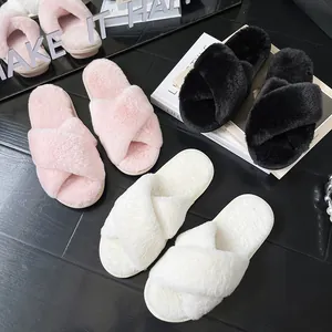 Dettaglio di pantofole in peluche rosa, bianche e nere con fasce incrociate.