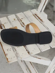 Detailed macro view showing the durable black anti-slip sole of retro tan flat sandals for women