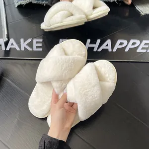 Primo piano di morbide pantofole in peluche bianco con cinturini incrociati