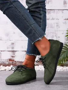 Detail view of olive green suede lace-up casual shoes with textured black sole