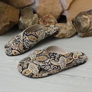 Close-up of ethnic paisley print flat slippers with crossover straps on wood floor