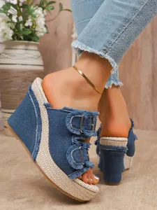 Close-up of blue denim wedge sandals with fringe detail and double buckle design