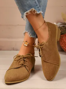 Detailed visual of women's brown suede pointed-toe lace-up shoes in casual setting