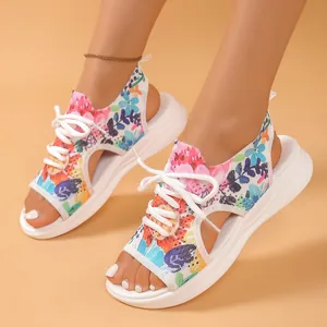 Gros plan de sandales de sport en maille fleurie avec des semelles blanches épaisses aux pieds.