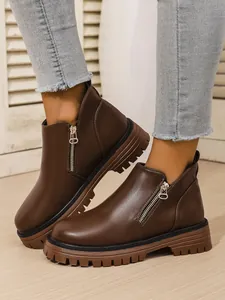 Close-up detail of stylish brown women's ankle boots with chunky soles and side zippers