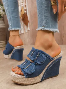 Close-up of denim platform wedge sandals with frayed straps and metal buckle details