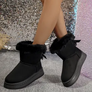 Close-up of black snow boots with plush fur trim and bow detail on a festive backdrop
