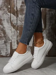 Side view of stylish white low-top platform sneakers with laces and denim jeans