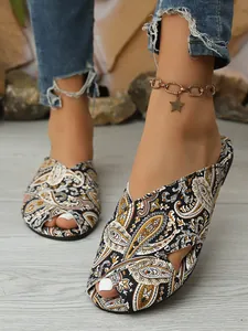 Close-up detail of ethnic style women's flat sandals with paisley print on model