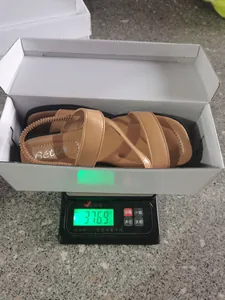 Nahaufnahme der Gewichtsmessung von braunen Vintage-Römersandalen in einem Schuhkarton