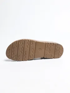 Detailed macro view of the non-slip brown rubber sole of women's Roman flat sandals