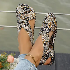 Close-up of ethnic style flat sandals with paisley print on a wooden deck