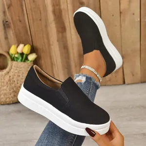 Detailed macro view of black suede slip-on sneakers with thick white platform sole.