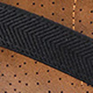 Macro view of perforated leather and chevron elastic strap detail on flat sandals