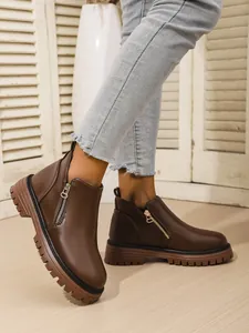 Close-up of brown faux leather ankle boots with side zipper and thick rubber lug sole