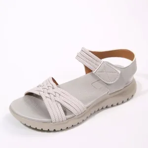 Elegant light grey women's flat sandals featuring woven straps and velcro ankle closure