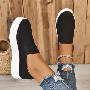 Close-up of black faux suede slip-on sneakers with white platform soles on model