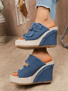 Detailed side view of stylish blue denim wedge platform sandals with fringe and buckle details