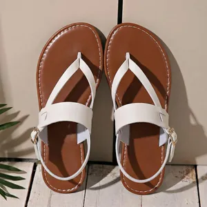 Overhead detail of white thong sandals with brown footbeds and buckle straps.