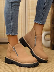 Detailed view of khaki suede ankle boots with side zipper and chunky lug sole.