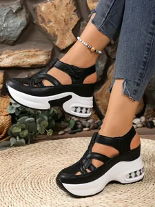 Detailed close-up of black closed-toe wedge sandals with white platform and velcro straps
