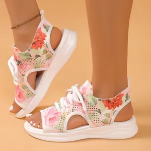 Gros plan de sandales de sport en maille à fleurs avec lacets blancs et semelles souples.
