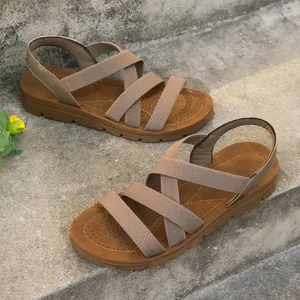 Close-up view of women's flat sandals with elastic cross-straps on concrete stairs