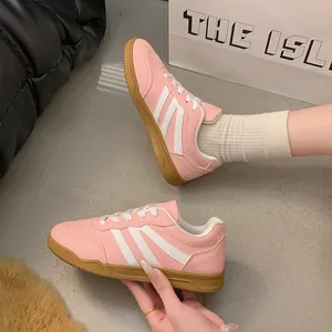 Gros plan de baskets rétro roses de style allemand avec rayures et semelles gomme.