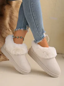 Detailed shot of white fuzzy snow boots with soft faux fur collar and suede finish.