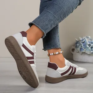 Detailed side view of women's white and burgundy German Army Trainer sneakers with gum sole.