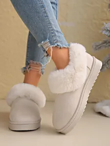 Detailed view of women's warm snow boots with thick faux fur trim and suede finish